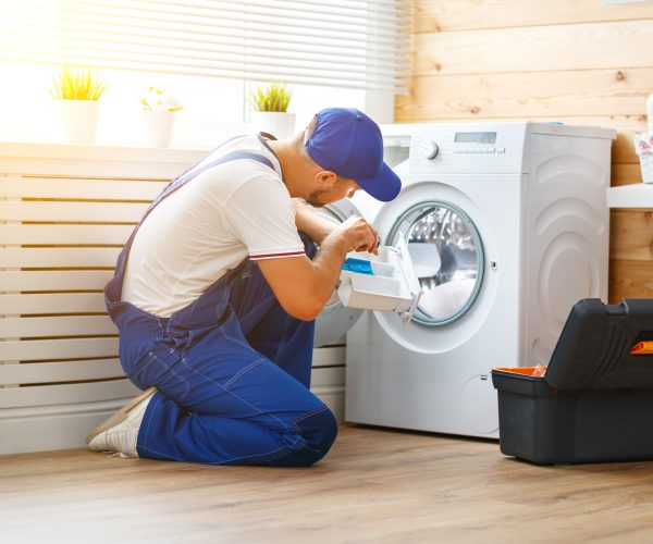 working man plumber repairs a washing machine in   laundry